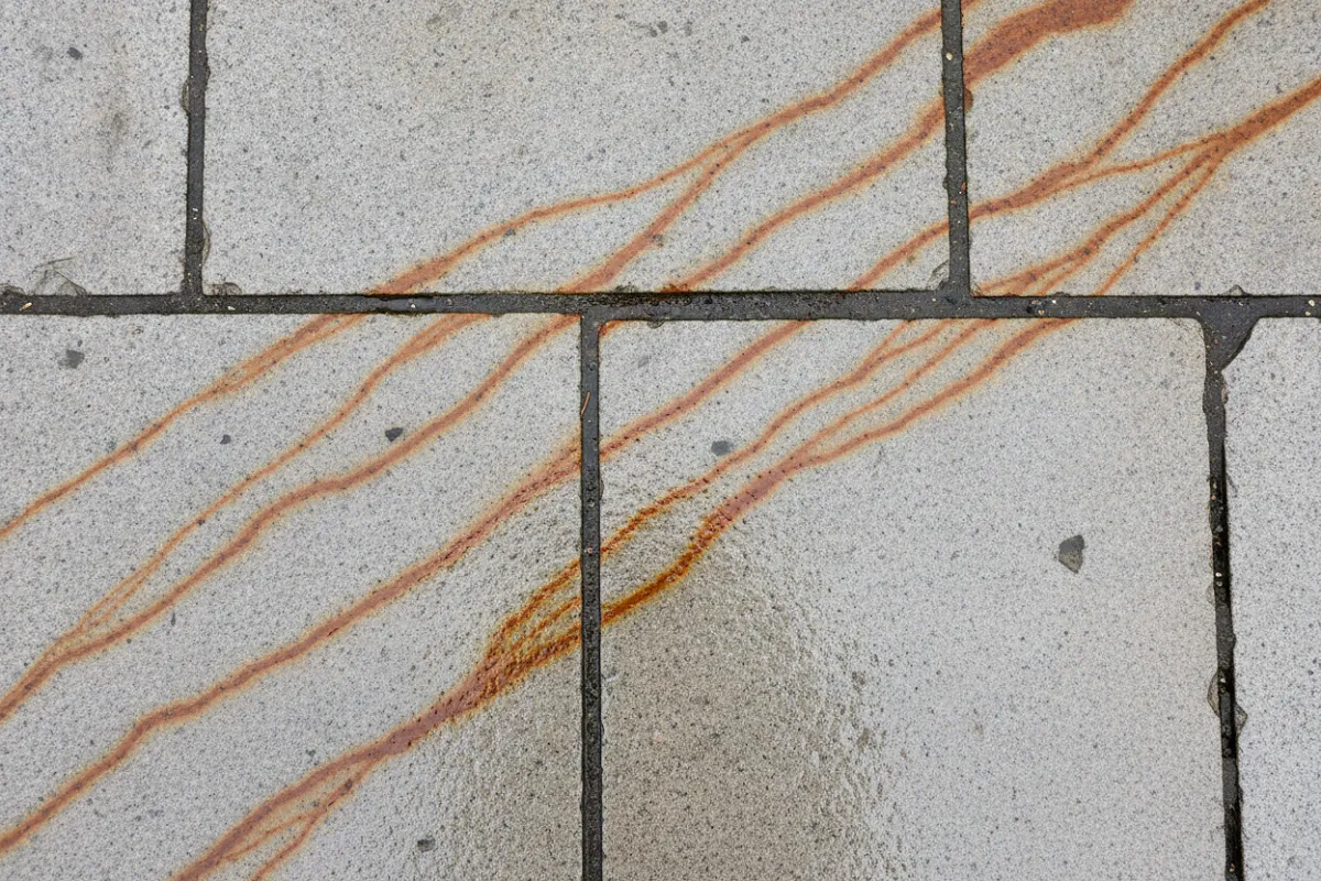 Des dalles de pierre claire marquées de coulures orangées laissées par la rouille entraînée par la pluie.