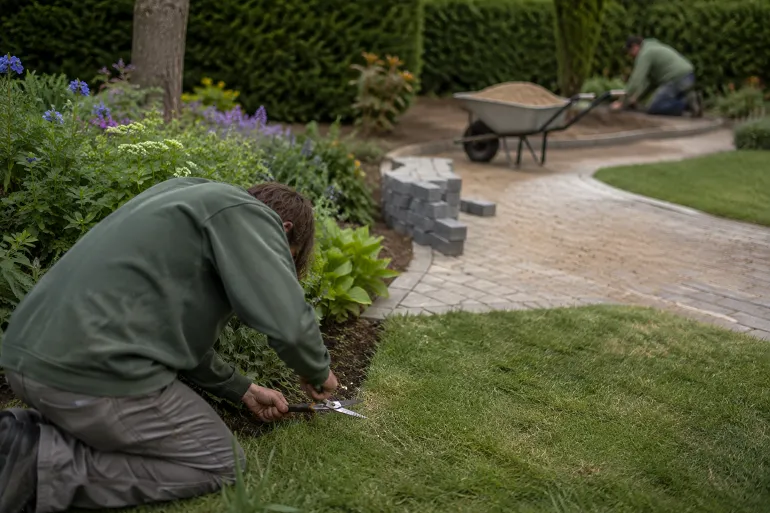 Un jardin où se croisent l'entretien d'un massif existant et un chantier d'allée en cours de pose