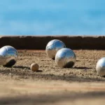 un terrain de pétanque avec 4 boules visibles et le cochonnet