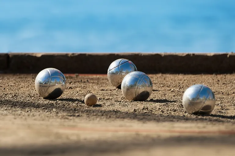 un terrain de pétanque avec 4 boules visibles et le cochonnet