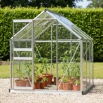 Choisir et réussir sa mini serre de semis 3 Petite serre de jardin ouverte au soleil, posée sur un lit de gravier